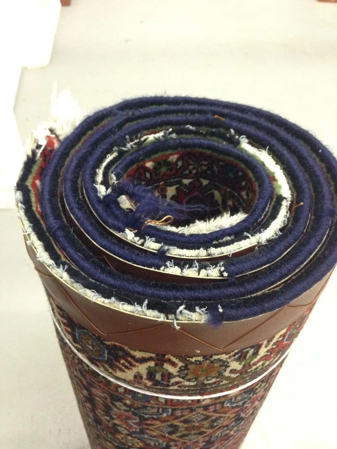 An oriental rug rolled up with its side edge exposed