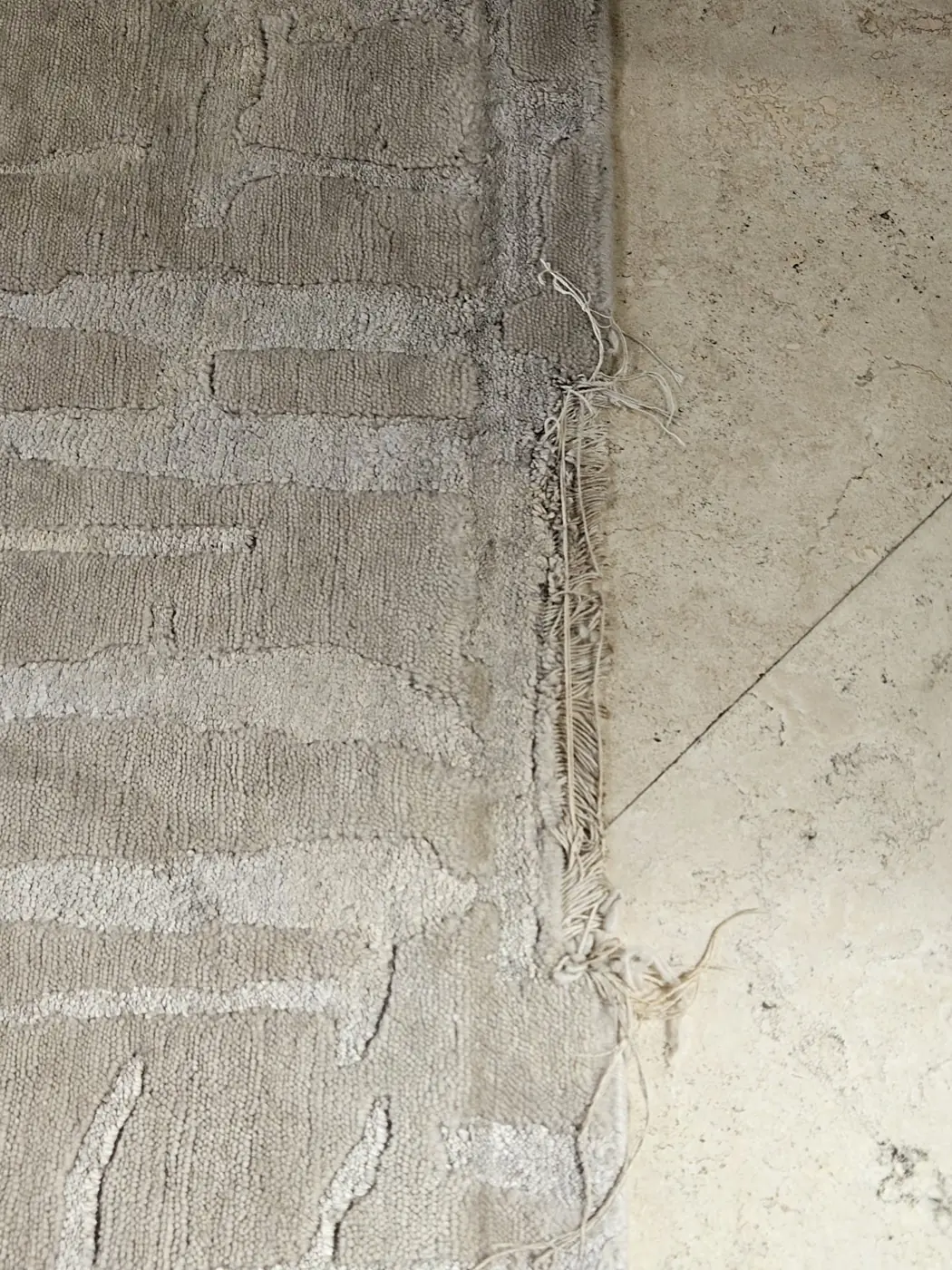 The worn end and exposed foundation of an oriental rug awaiting repair